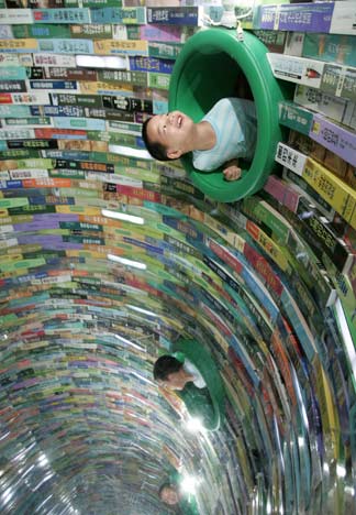 A child looks inside a tunnel made out of books during the "Diversity of Taiwan 2006" exhibition in Taipei, July 30, 2006. [Reuters]