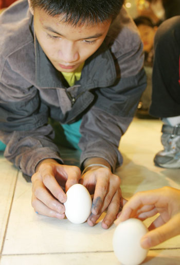Taiwaneses try to stand an egg stand during the annual Dragon Boat Festival in Taipei May 31, 2006. Egg-standing at noon is a custom that takes place during the Dragon Boat Festival, commemorated in memory of the drowned poet Qu Yuan.