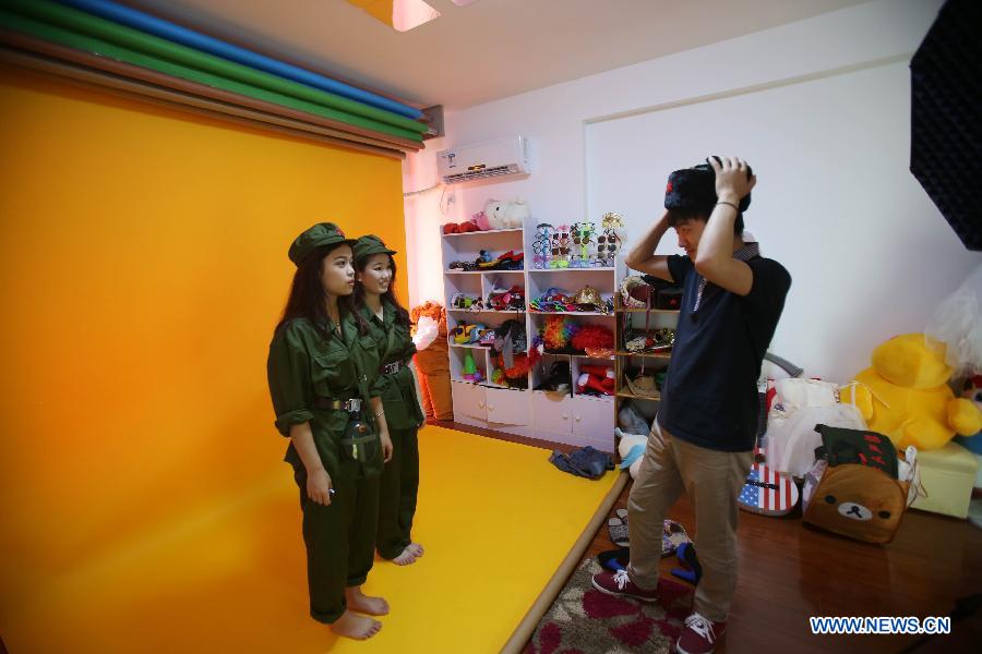 Zeng Jun offers posture guidance to two customers at his photo studio Takaphotoo in Changsha, capital of central China's Hunan Province, April 15, 2014.