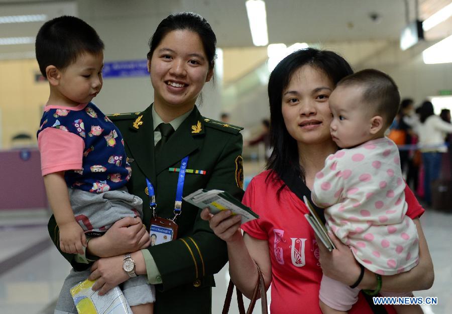 A staff member (2nd L) of the frontier inspection station provides service for Ms. Zheng (2nd R) and her children at the airport of Fuzhou, capital of southeast China's Fujian Province, April 4, 2014. Ms. Zheng is one of the over 400 people from Taiwan who returned to Mazu and Mawei in Fujian Friday for tomb-sweeping and mourning for their deceased family members during the Qingming Festival. Fuzhou witnessed surging of Taiwan compatriots returning in the recent week. (Xinhua/Zhang Guojun)